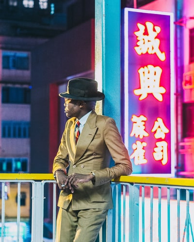男人棕色外套戴着黑色帽子站在红色和黄色墙
